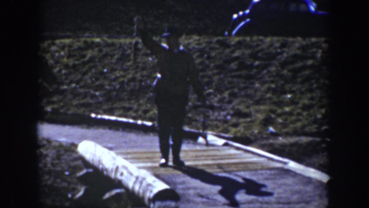 1939 Yellowstone home-movie frame showing a man on a boardwalk beside steam and mineral ground.
