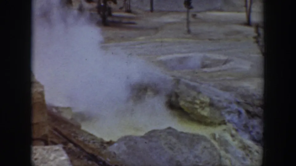 Yellowstone thermal pool with heavy steam, yellowish water, and mineral crust in archival 8mm footage.
