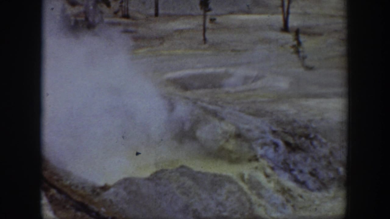 1939 Wyoming 8mm frame showing steam over pale mineral terrain and a bubbling hot-spring or geyser edge.