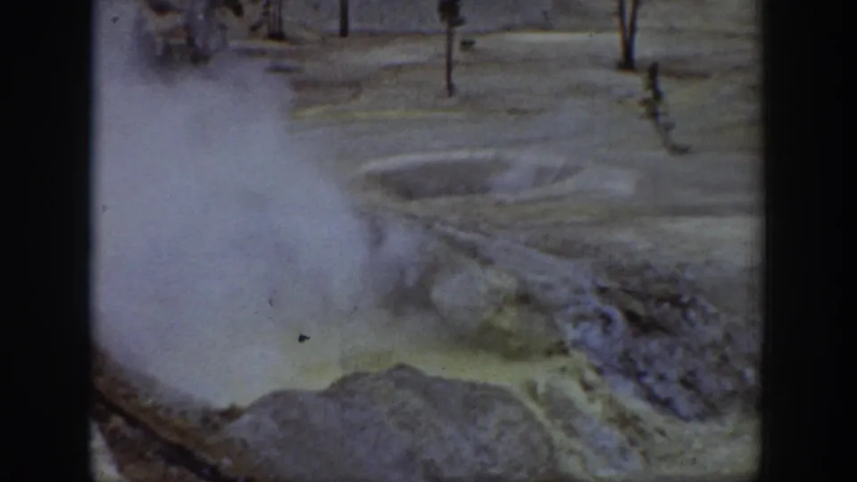 1939 Wyoming 8mm frame showing steam over pale mineral terrain and a bubbling hot-spring or geyser edge.