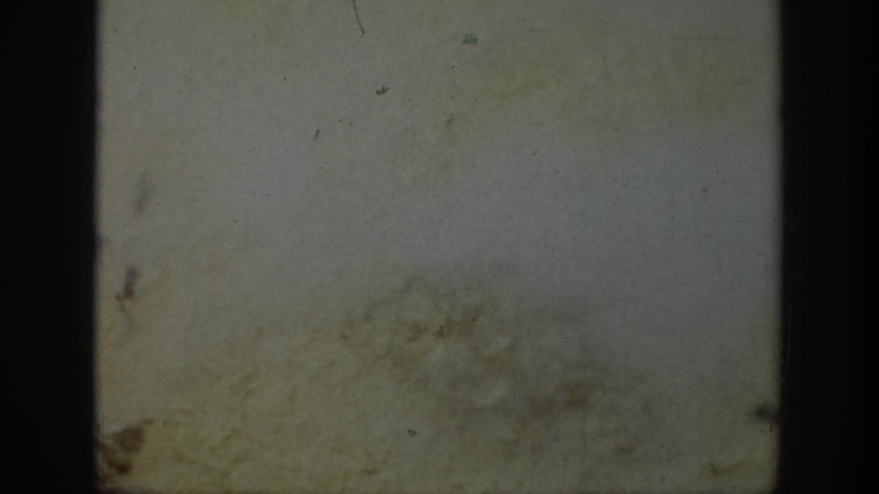 Mostly blank faded frame with dark film gate edges and surface marks.