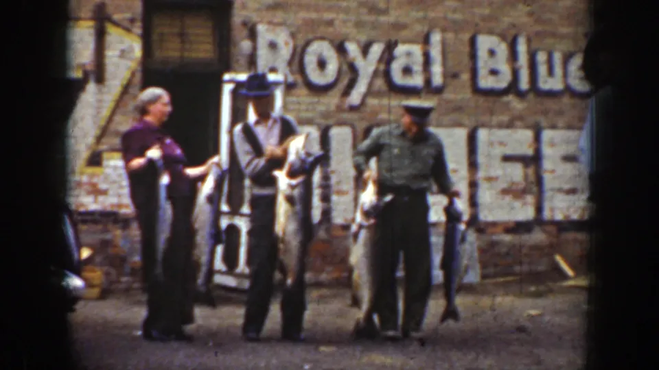 Three adults in 1939 Wyoming metadata pose with several large fish, with hats, work clothing, and a faded wall sign visible behind them.