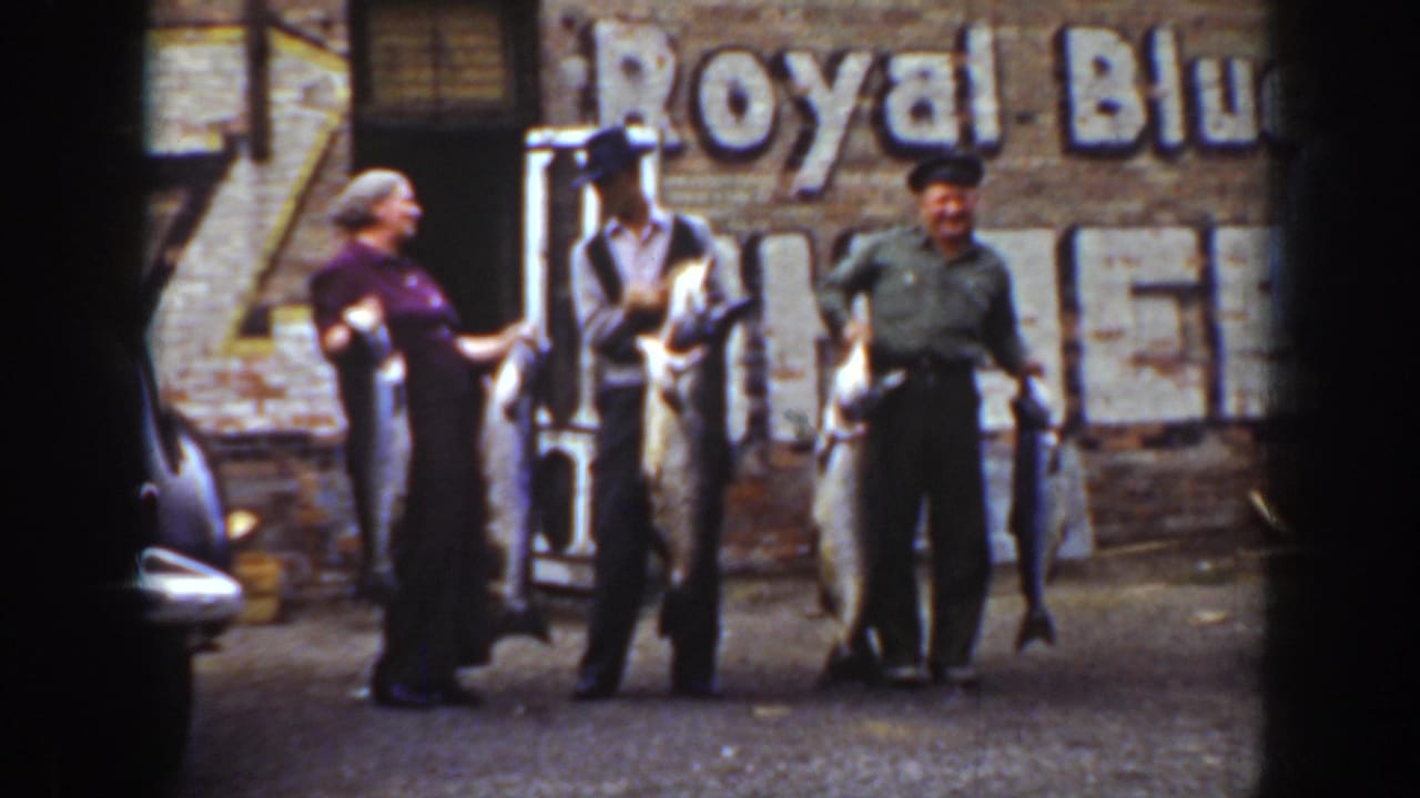 Three adults in 1939 Wyoming stand with large fish in front of a brick wall with a faded Royal Blue sign.