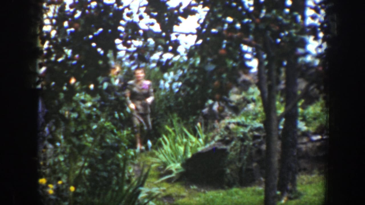 In 1939 Wyoming home-movie footage, a suited couple appears in a wooded area with shrubs, grasses, and dark tree trunks.