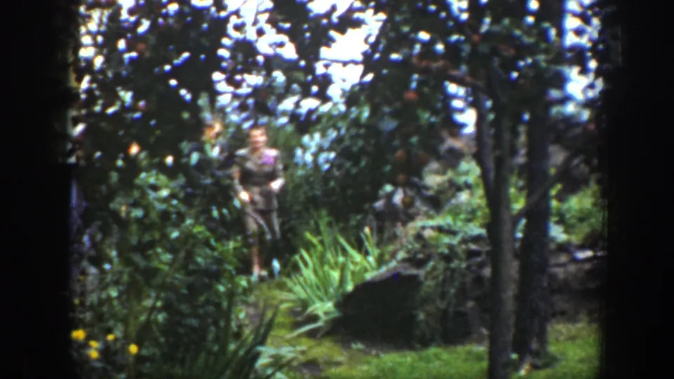 In 1939 Wyoming home-movie footage, a suited couple appears in a wooded area with shrubs, grasses, and dark tree trunks.