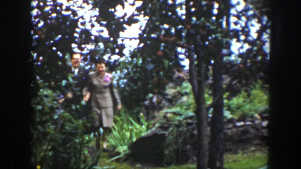 In the 1939 Wyoming clip, the woman walks forward through the wooded path with a suited man partly visible behind her.
