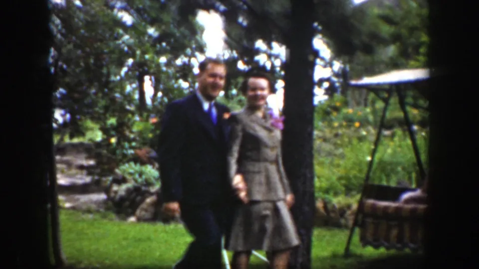 The 1939 Wyoming home-movie frame shows the couple close together in the garden, with a porch swing at the right edge.