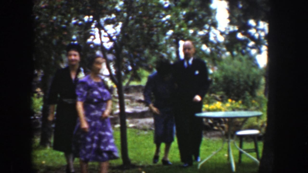 Adults in suits and dresses appear in a Wyoming garden setting, with trees, lawn, yellow flowers, and patio furniture visible.