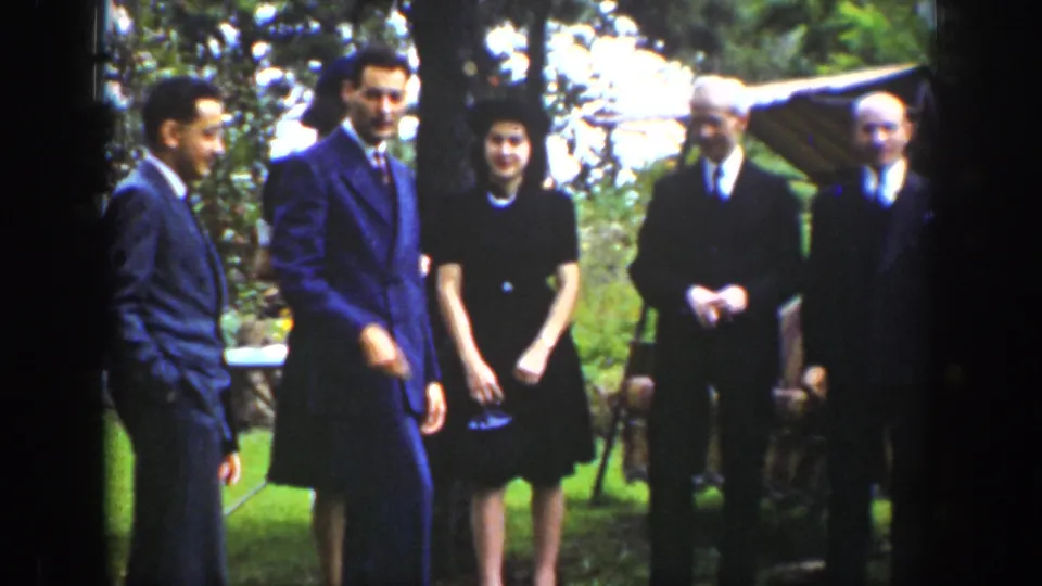 The 1939 Wyoming home movie shows adults in suits, ties, hats, and dark dresses gathered on a lawn and facing the camera.