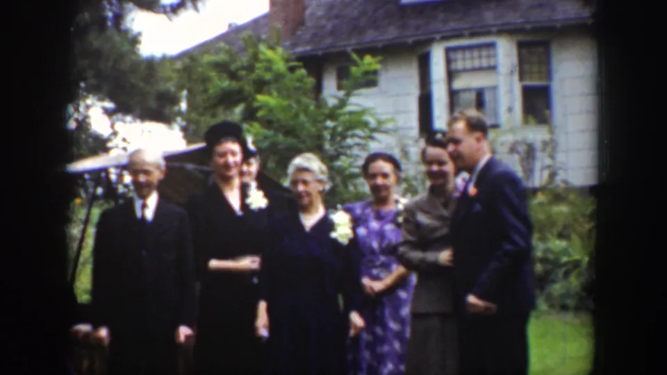 Adults in suits and dresses pose together outside a light-sided house in Wyoming 1939 8mm home-movie footage.