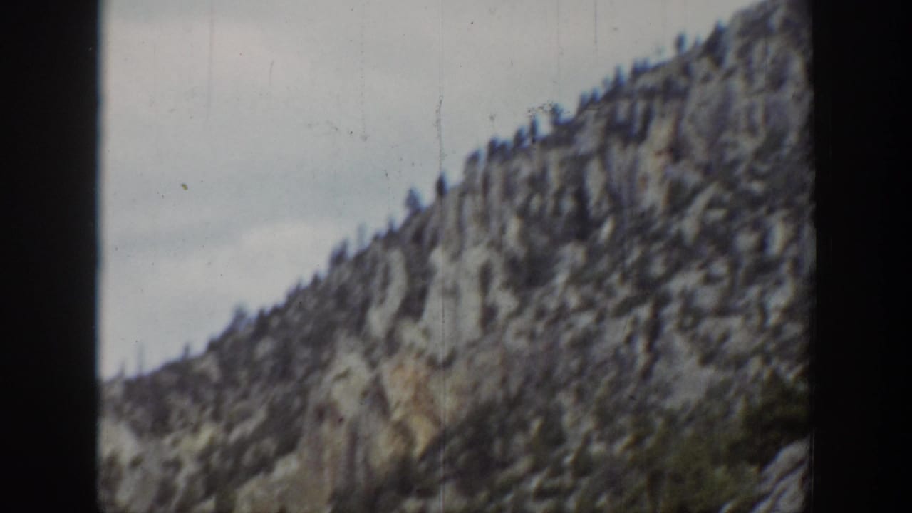 1939 Wyoming 8mm frame showing a jagged mountain slope with scattered trees and soft handheld focus.
