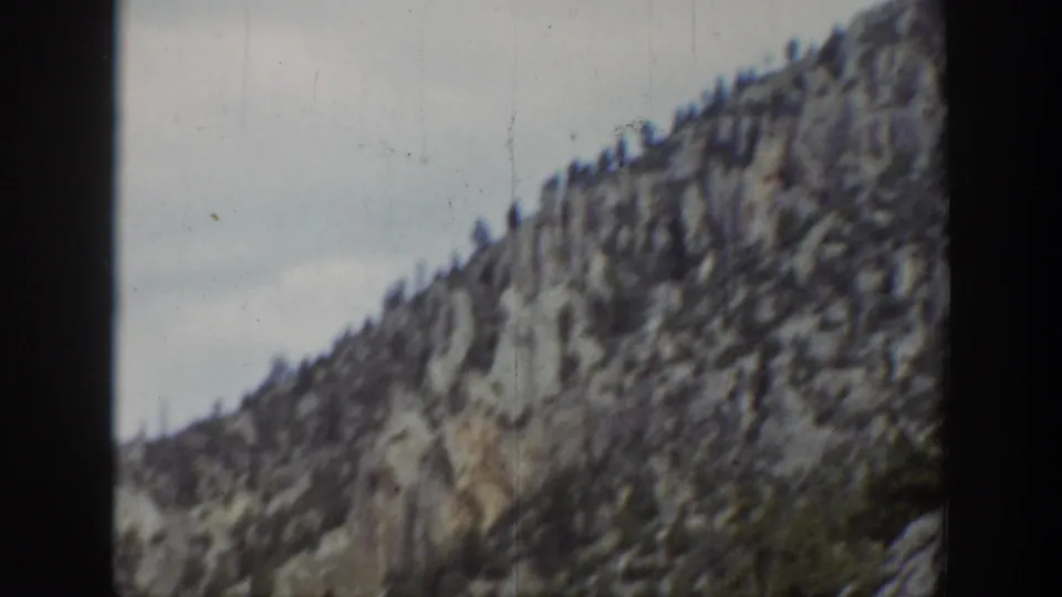 1939 Wyoming 8mm frame showing a jagged mountain slope with scattered trees and soft handheld focus.