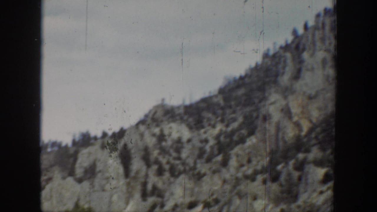 Mountain ridge and rocky slope framed beside a dark film edge.