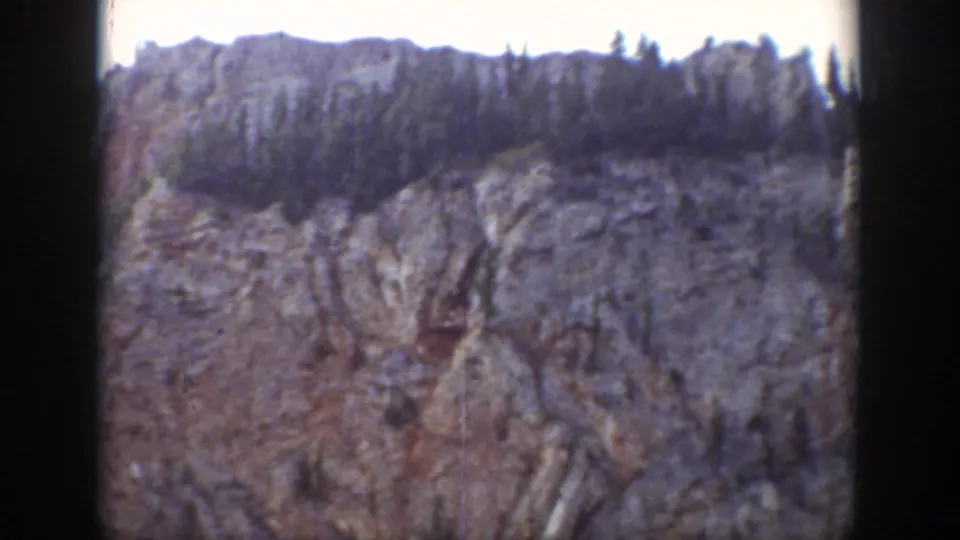 1939 Wyoming 8mm frame showing a rugged rock face with a line of trees near the upper ridge.
