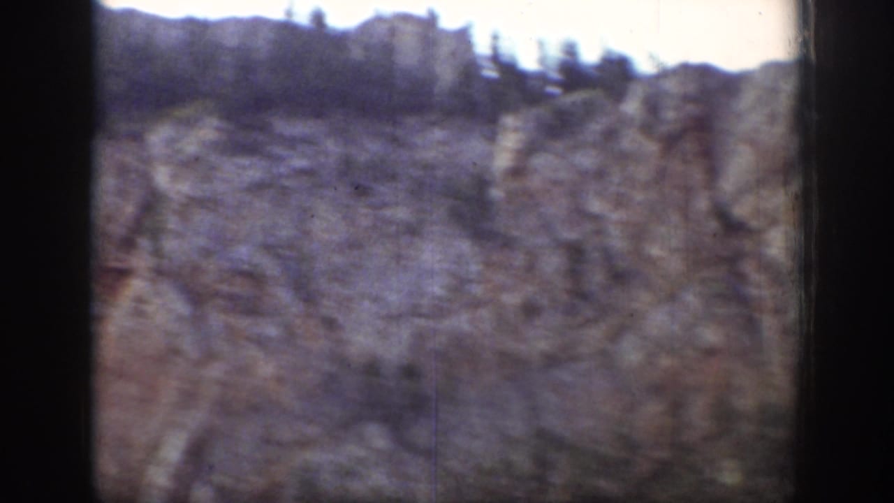 Rocky cliff landscape with dark 8mm borders and blurred foreground motion.