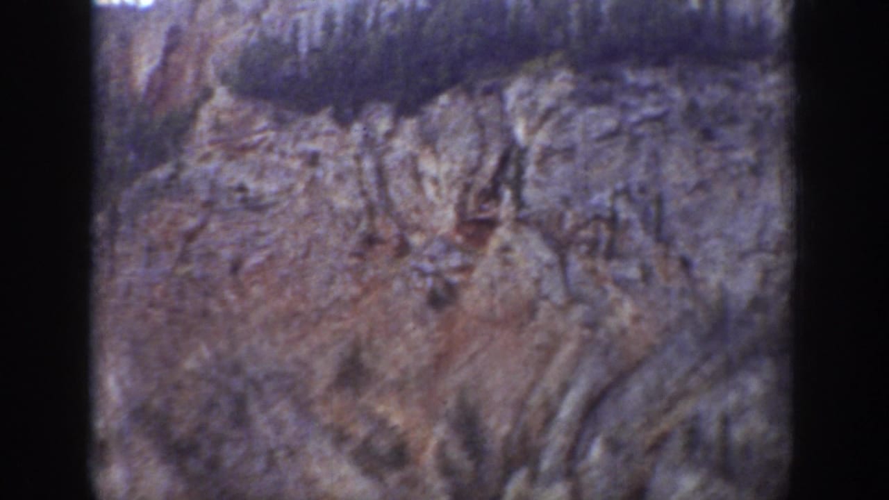 1939 Wyoming 8mm frame showing a steep, jagged rock face with sparse trees along the upper ridge and soft home-movie focus.