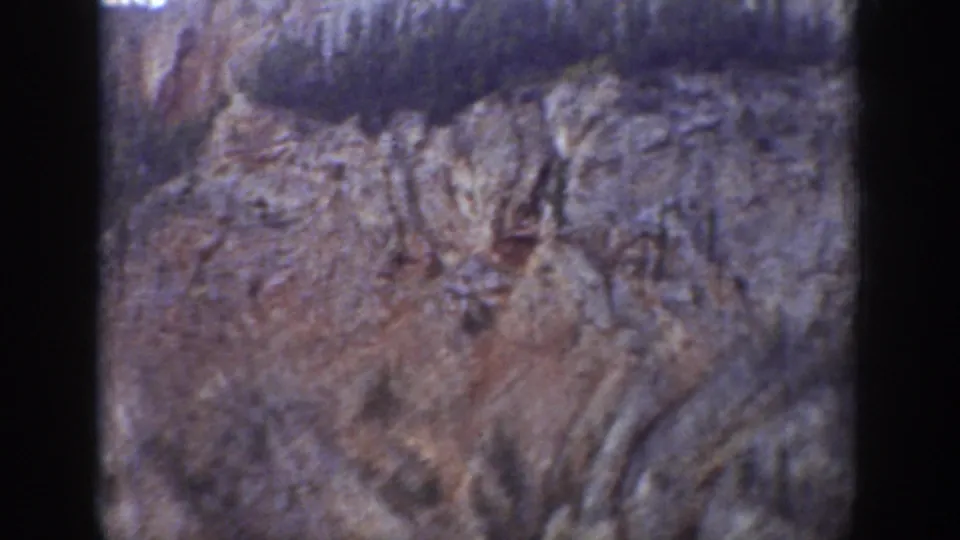 1939 Wyoming 8mm frame showing a steep, jagged rock face with sparse trees along the upper ridge and soft home-movie focus.