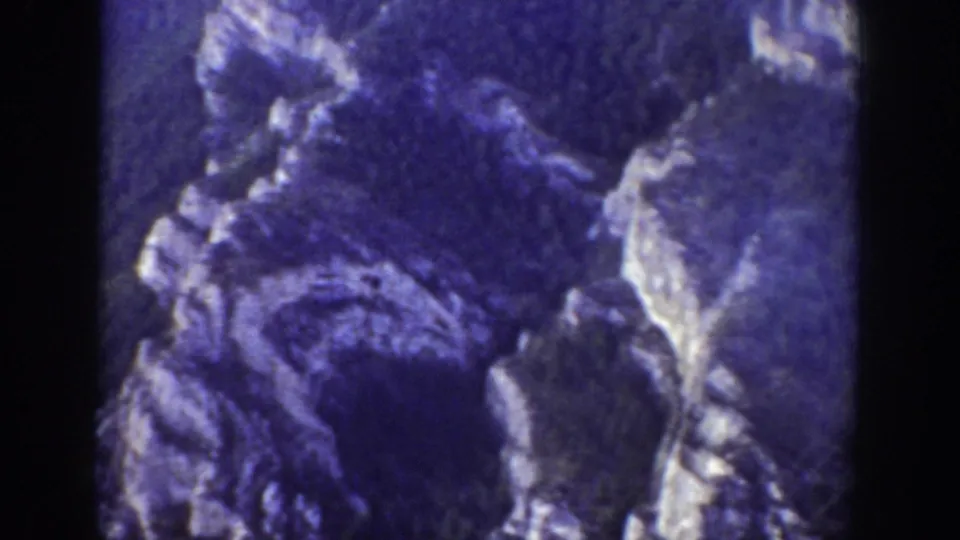1939 Wyoming 8mm frame focused on jagged mountain rock surfaces with pale snow or light-toned patches and soft film grain.