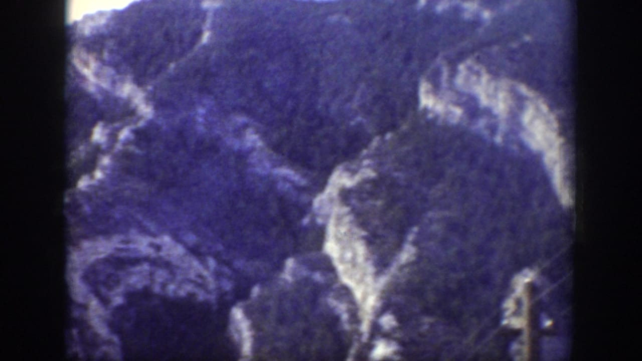 Mountain ridge with pale rock outcrops and dense dark forest.