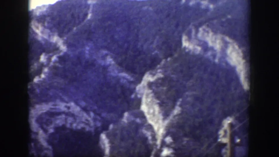 1939 Wyoming landscape view with forested mountainsides and pale rock formations visible through soft 8mm color.