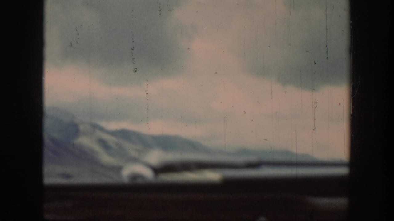 Distant mountains and cloudy sky seen through a car windshield above a dark dashboard.