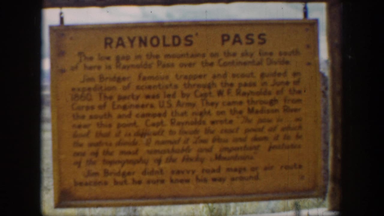 Weathered Reynolds' Pass sign with dark text on an orange background.