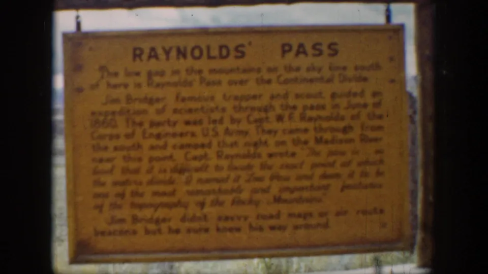 1939 Wyoming home-movie frame showing a Reynolds' Pass historical sign in soft focus with visible 8mm film wear.
