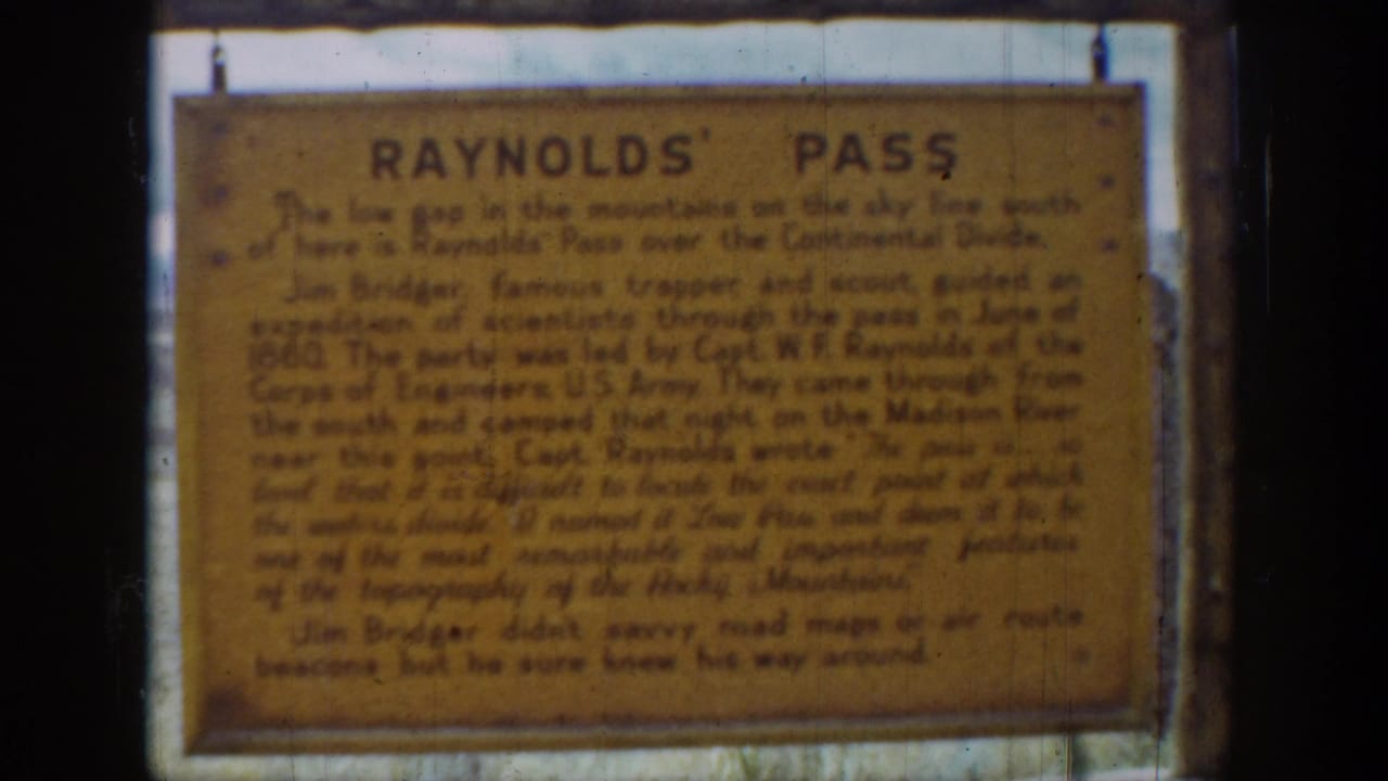 1939 Wyoming home-movie frame showing a weathered yellow Reynolds' Pass historical sign in soft 8mm focus.