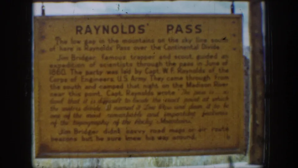 1939 Wyoming frame of the Reynolds' Pass marker, showing the aged sign surface, support rods, and grass below.