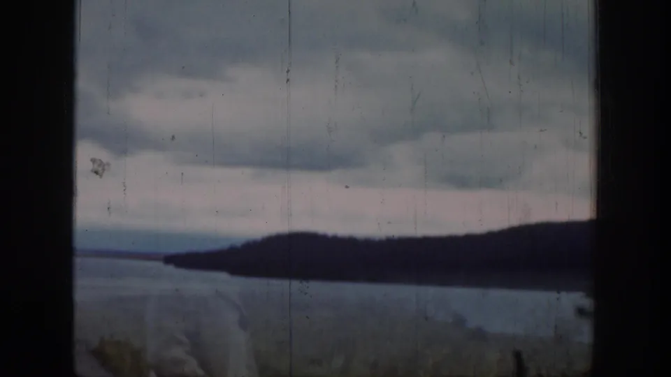 A 1939 Wyoming home-movie view of water, low hills, cloudy sky, and foreground obstruction from a window or vehicle opening.