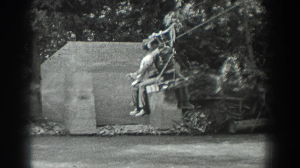 The rider passes a concrete shed-like structure on a simple outdoor cable ride in this 1940 Washington home-movie frame.