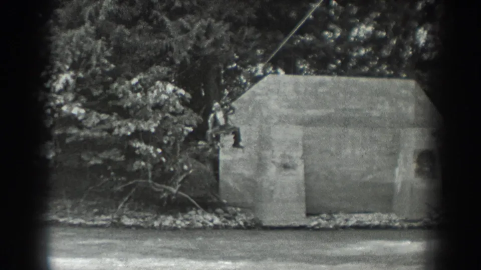 1940 Washington 8mm frame showing two people on a rope near a small concrete riverside structure, with trees and water behind them.