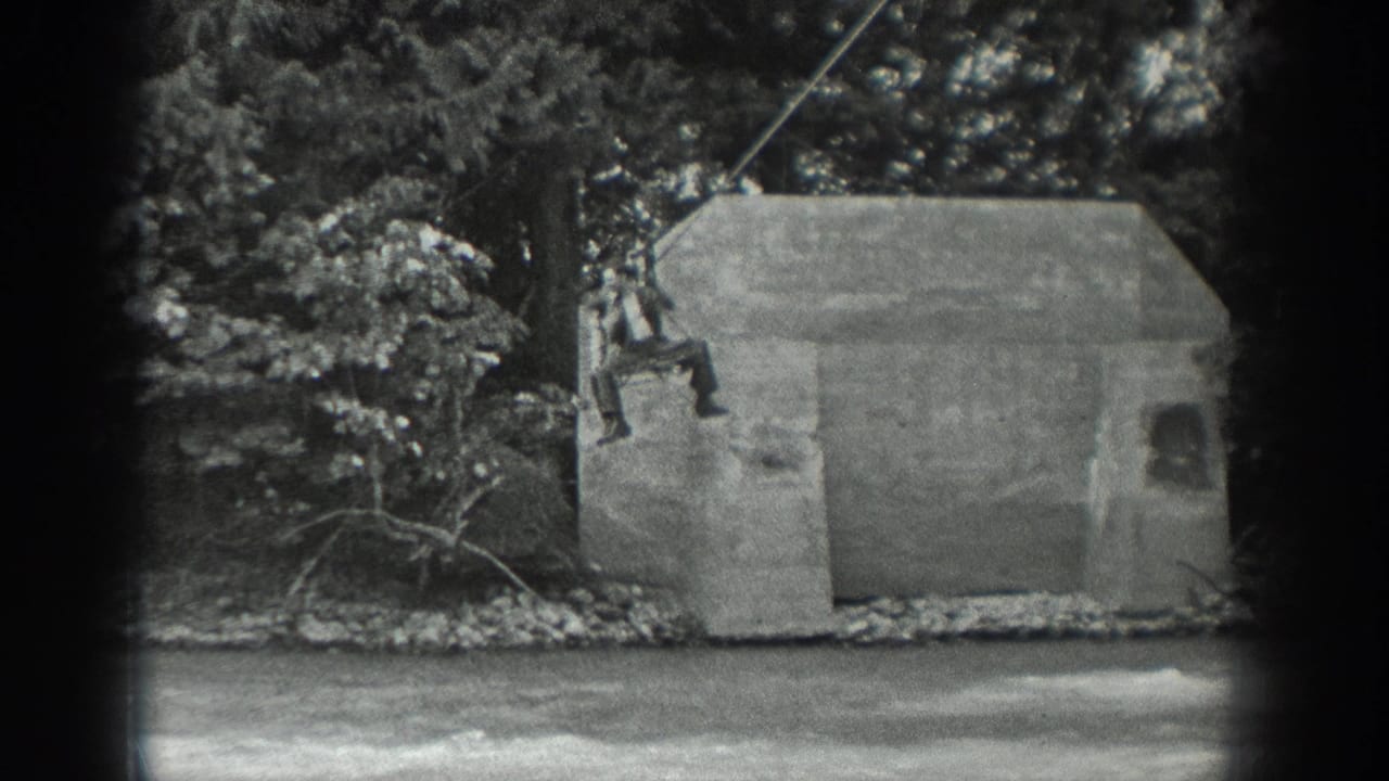 In this 1940 Washington 8mm frame, a man rides a suspended cable beside a concrete structure over or near a river.
