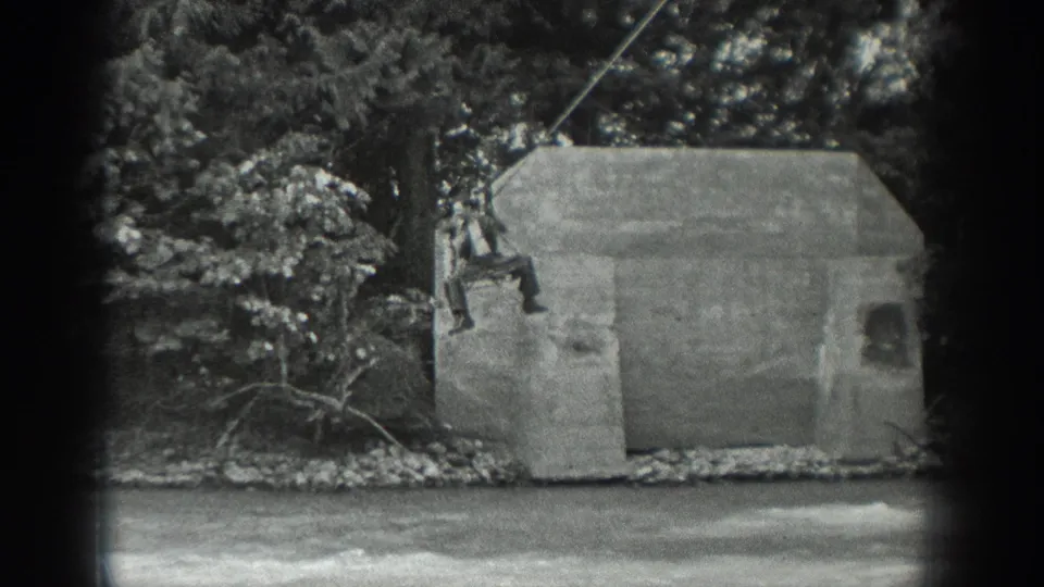In this 1940 Washington 8mm frame, a man rides a suspended cable beside a concrete structure over or near a river.
