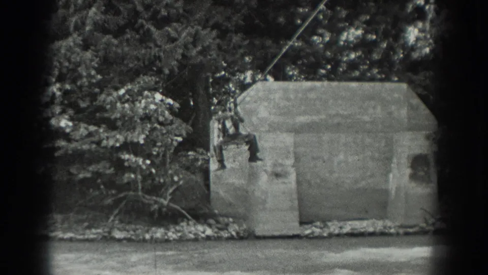 The rider continues along the cable in a wooded Washington riverside scene, with a concrete structure below and trees behind.