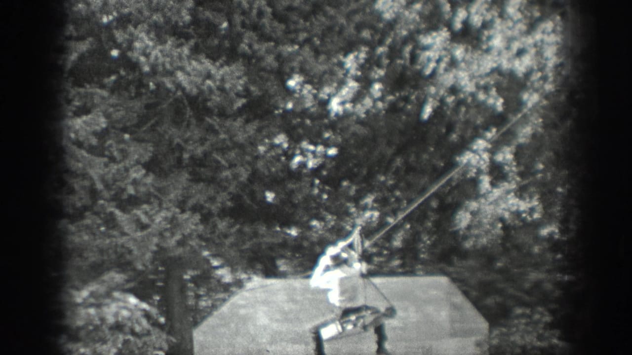 The man continues the 1940 Washington line crossing, leaning back as he grips the rope or clothesline above the platform.