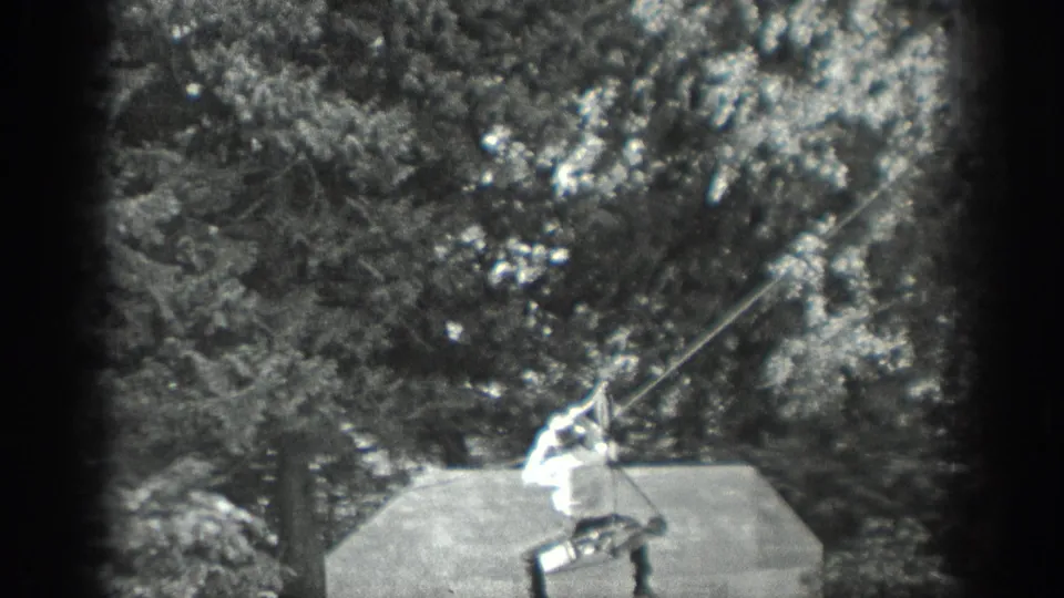 The man continues the 1940 Washington line crossing, leaning back as he grips the rope or clothesline above the platform.