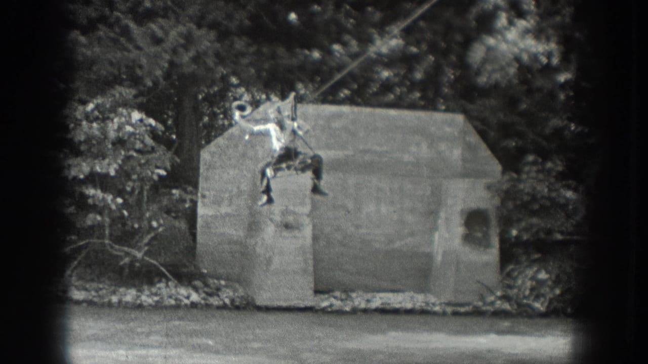 Man seated on a suspended cable ride above a concrete structure in a wooded area.