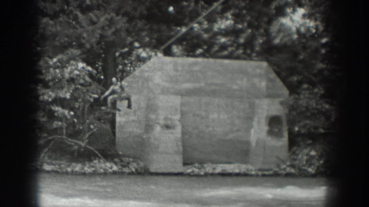 1940 Washington black-and-white frame showing a riverbank concrete structure, trees, and overhead cable before the rope platform enters view.