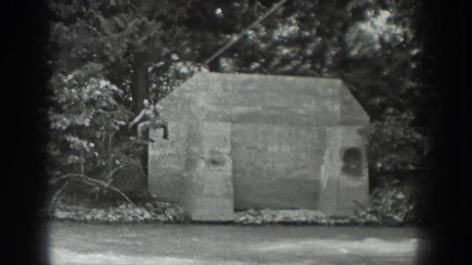 1940 Washington black-and-white frame showing a riverbank concrete structure, trees, and overhead cable before the rope platform enters view.