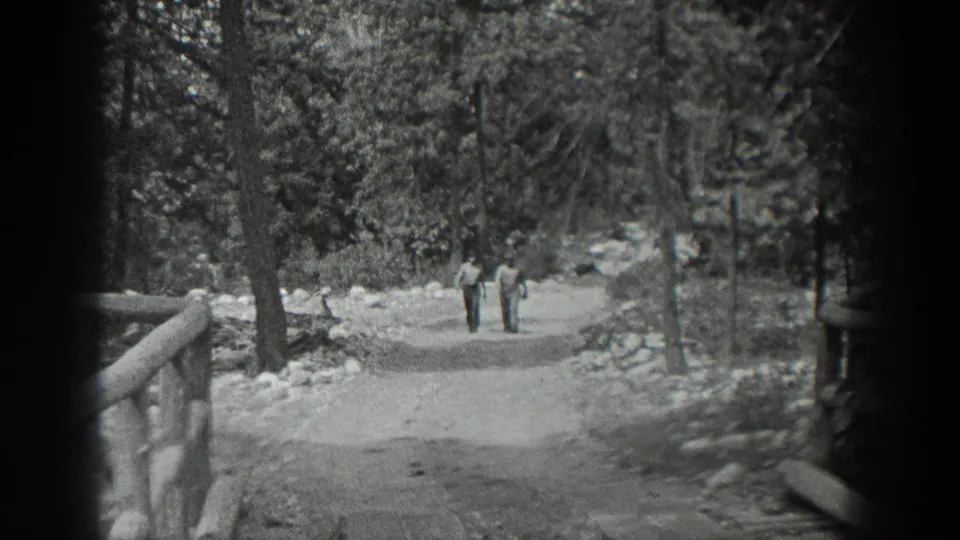 Washington, 1940 home-movie frame showing two men on a forest trail, with a rustic railing and rocky edges along the path.