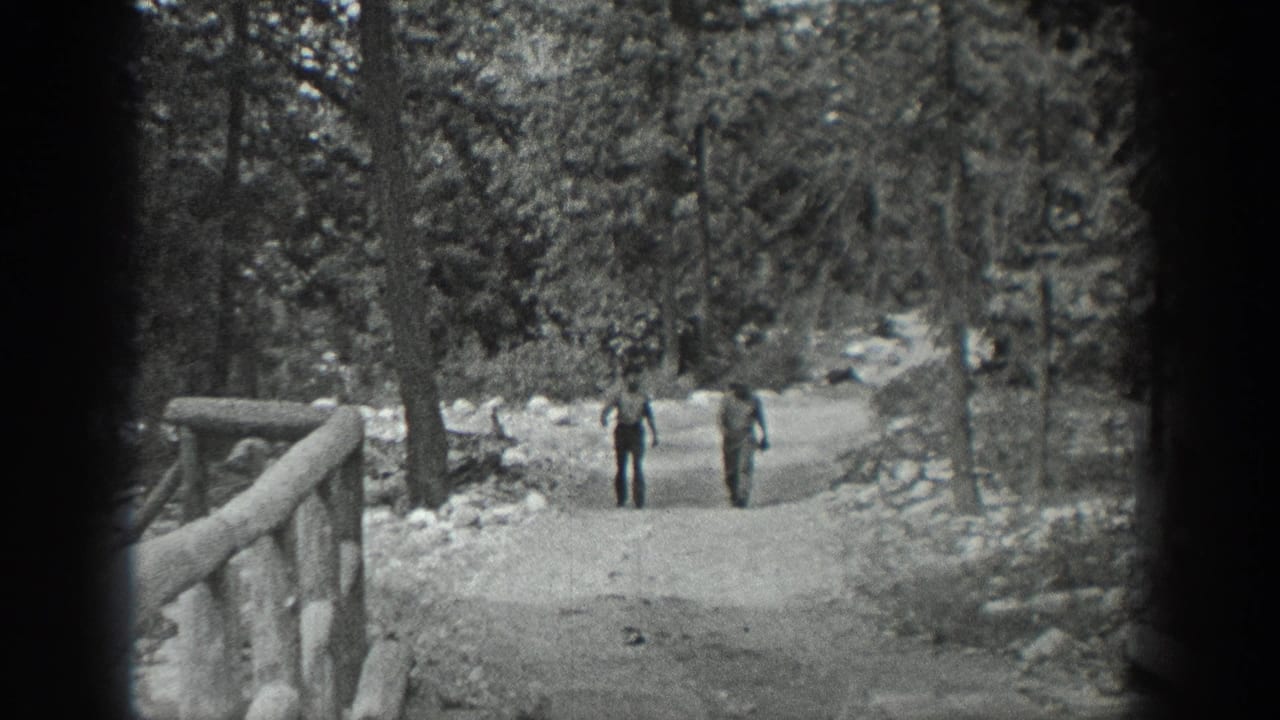 Two men walk side by side along a curving wooded path.
