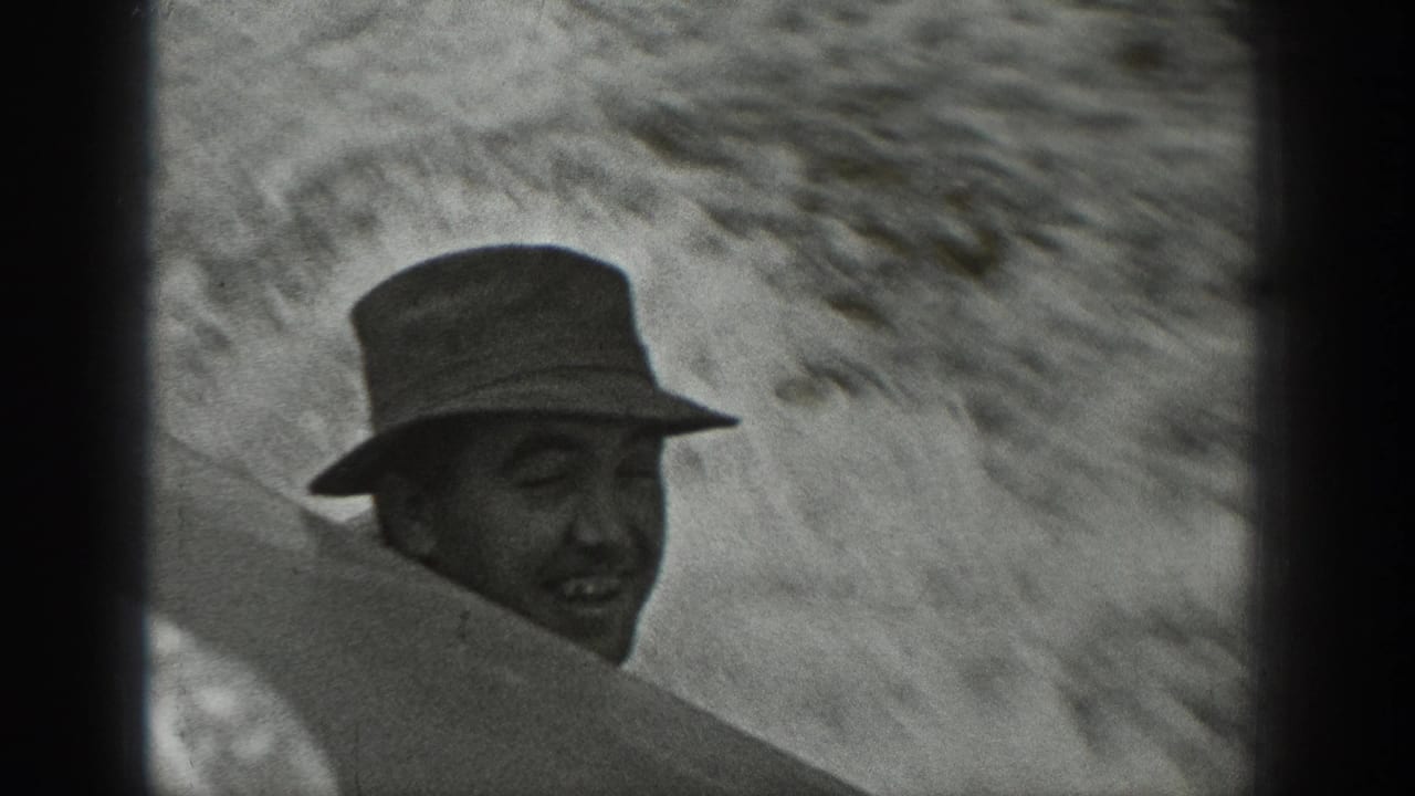 Man in a brimmed hat smiles from behind part of a boat structure.