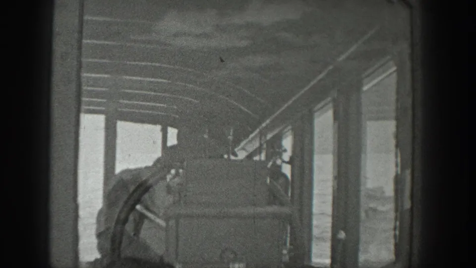 The camera looks down a Washington boat cabin with window frames, roof ribs, and passengers seated or standing inside.