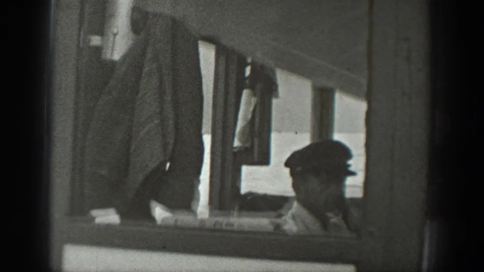 1940 Washington 8mm frame showing a seated man in a cap partly framed by the side of a small boat.