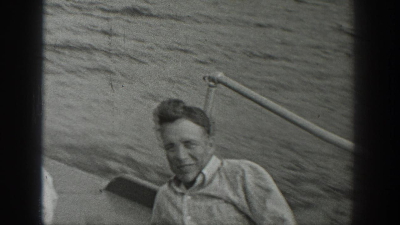 Young man smiling on a small boat with water behind him.