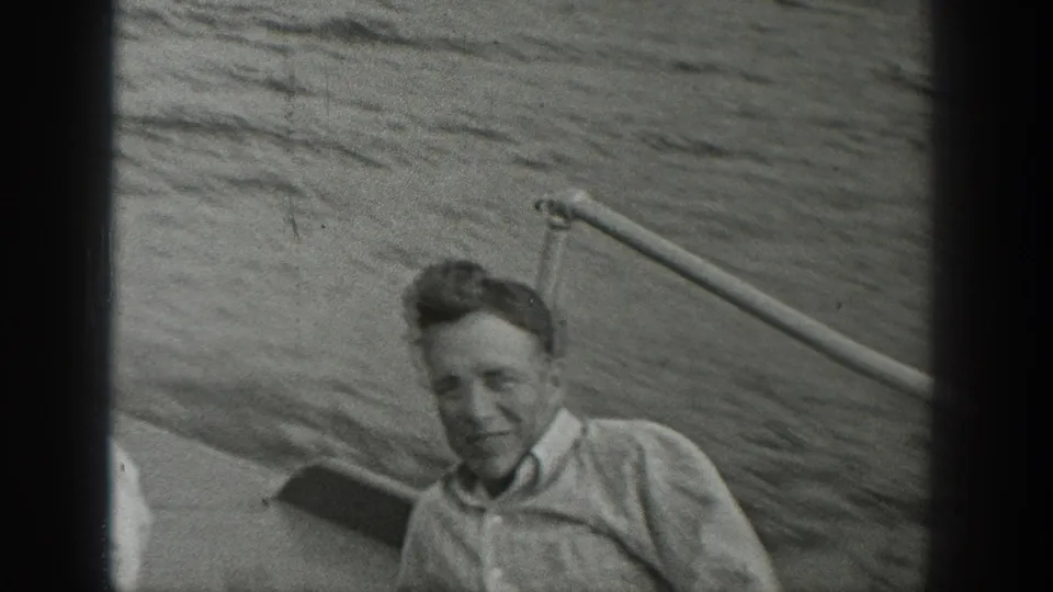 Young man aboard a small boat in the 1940 Washington home-movie clip, smiling as water fills the background.