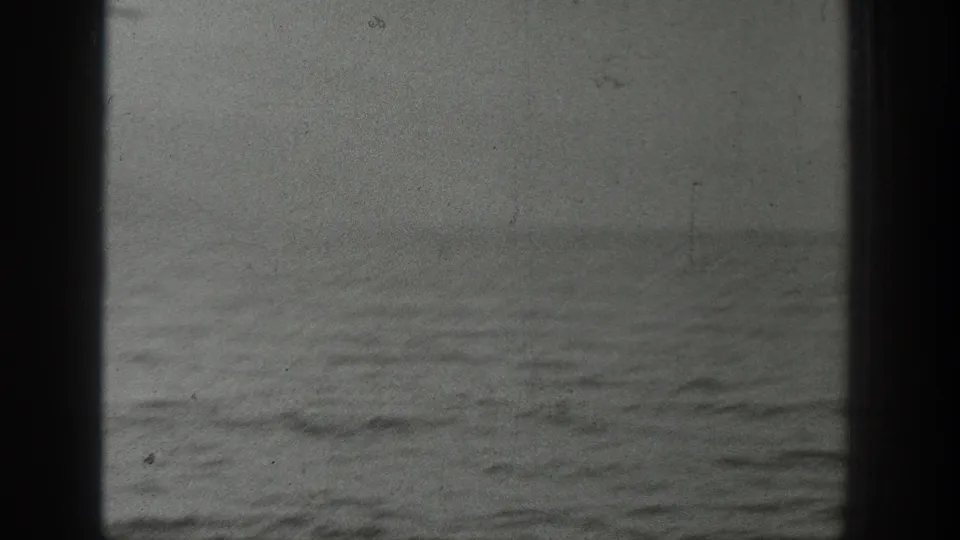 Soft 8mm frame of water and a faint horizon from the Washington boating footage, with visible grain and gate edges.