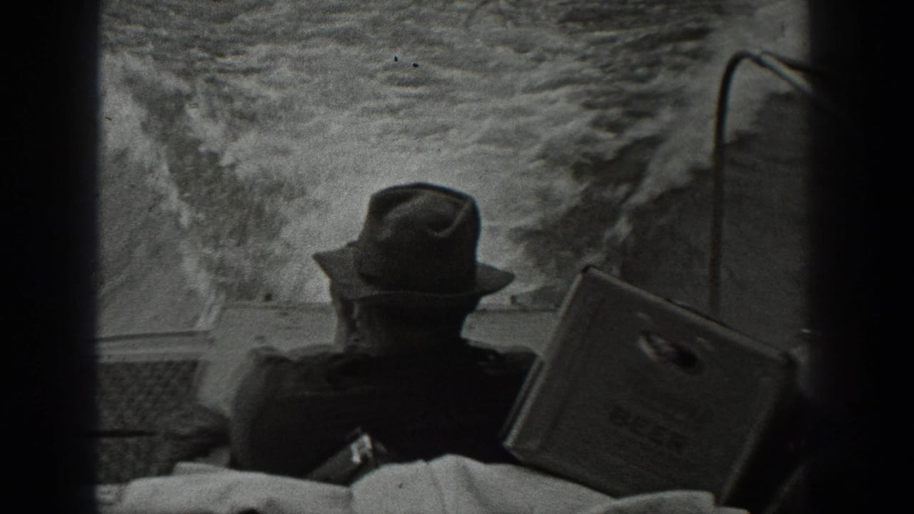 1940 Washington home-movie frame showing a fedora-wearing man seen from behind on a boat, with wake and spray filling the background.