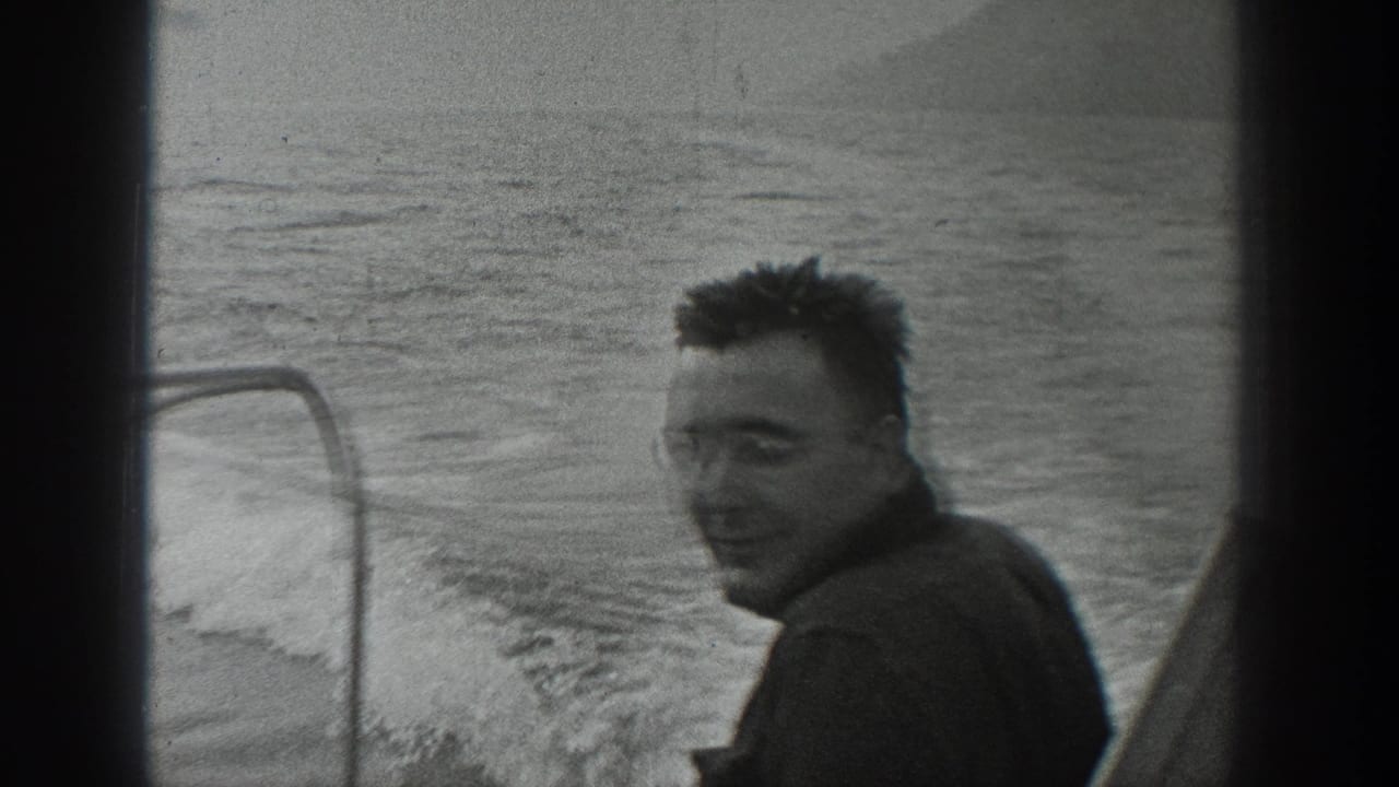 Smiling man on a boat with water and wake behind him.